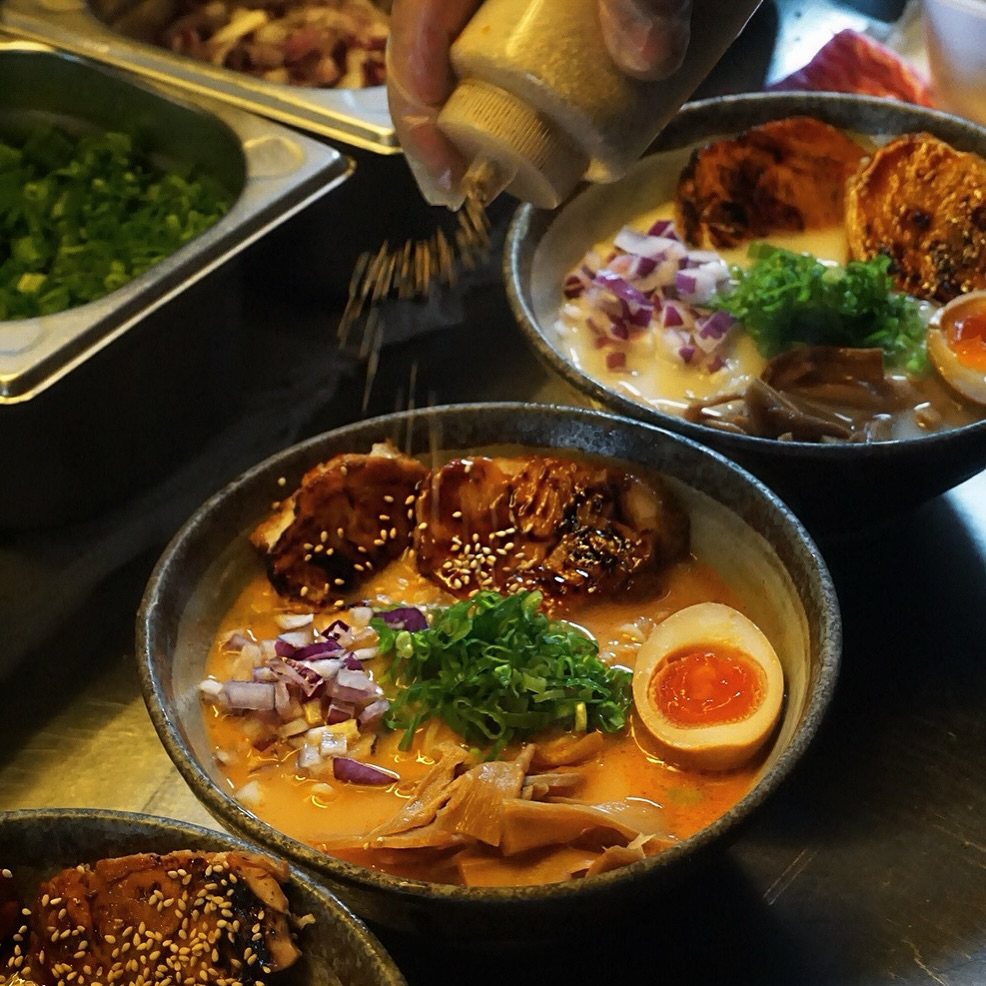 Ramen werden in der Küche des DAIKAN mit Toppings vollendet